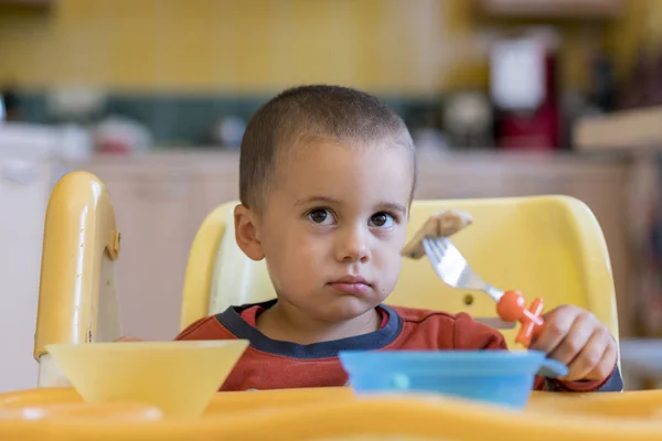 Хлопчик 2 роки їсть м'ясо. Дитячий стіл. Концепція незалежності дитини. смішна дитина на дитячому сидінні . — стокове фото