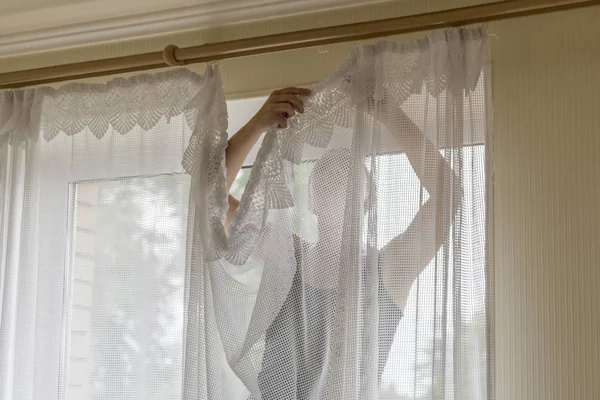 Woman hanging curtains on windows. Housekeeper hangs curtains.