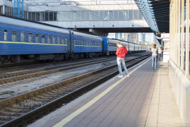Bir tren istasyonundaki adama bekliyor. demiryolu platformu üzerinde kırmızı kazaklı adam. bulanık.