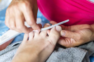 Eldiven umurunda elinde çivi ayak. Pedikür güzellik salonu. Tırnakları ile dosya dosyalama. yakın çekim.