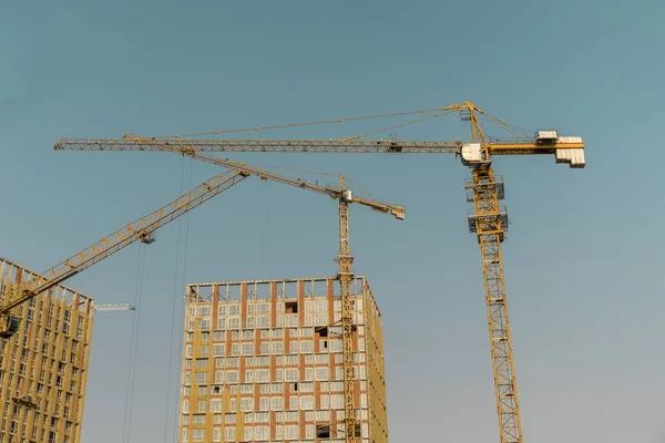 Hoisting crane and new multi-storey building. ndustrial background. Construction of high-rise houses and hoisting tower cranes. New multi-storey housing and large crane.