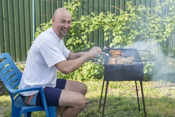 Yakışıklı adam Barbekü arkadaşlar için hazırlanıyor. Genç çift kendi bahçesinde barbekü yapma