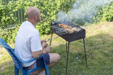Adam pişirme et mangal üzerinde. Genç çift kendi bahçesinde barbekü yapma. Barbekü üzerinde pişirme et dostum.
