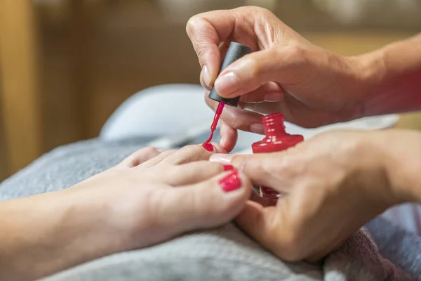 女性の足の爪を気に手袋の手 ペディキュア マニキュア美容サロン コンセプト 爪の赤い色でニスを塗る — ストック写真