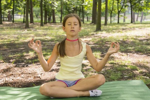 女の子の幸せと瞑想ヨガ子供公園でヨガの練習 健康的なライフ スタイル 女の子公園でヨガをすること 健康とヨガのコンセプト — ストック写真