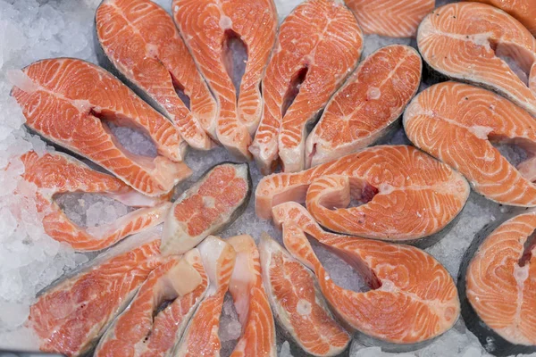 氷の上の美しい赤いステーキの横にサーモンの切り身 スーパーで氷に新鮮な生サーモン ステーキを食べるのたくさん 氷の上の新鮮な生鮭 大きな生鮭 — ストック写真