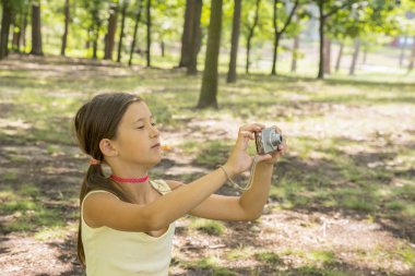 Küçük kız çocuğu 8 yıl Şehir Parkı yeşil çimenlikte oturan kamera bakıyor. Kız 8 yıl doğa fotoğraflarını Park.