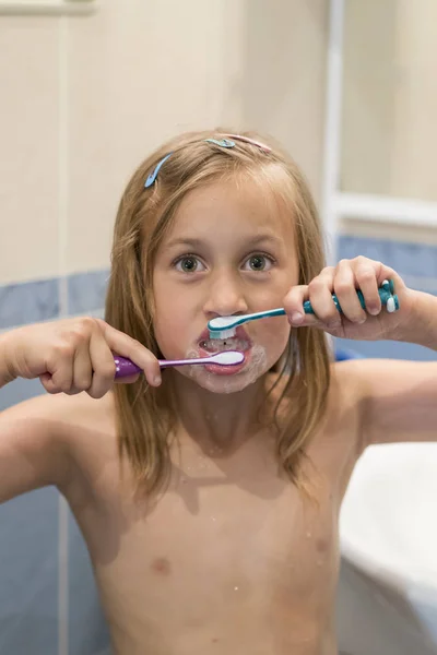 Küçük kız ile iki fırçalar diş fırçaları. Stomatology. sözel sağlık kaygı. dikey fotoğraf.