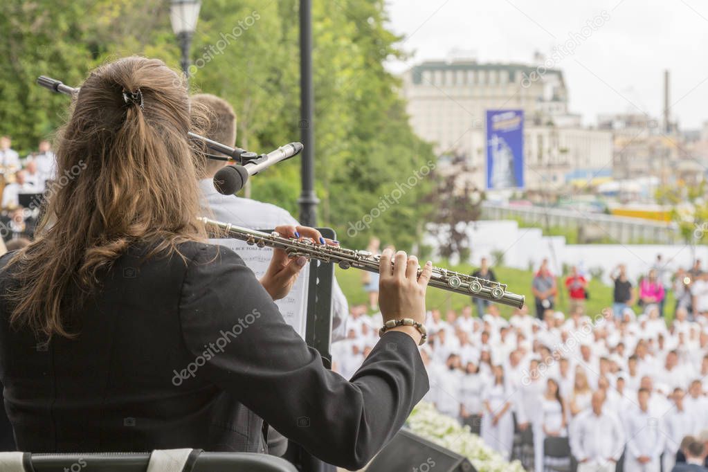 Girl playing the flute in the park. woman playing flute. game on a musical instrument flute at event. flute is close-up.