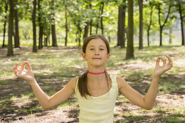 girl\'s happy and Meditate on the practice of yoga in the park , yoga kid. Healthy lifestyle - little girl doing yoga in the park. Healthy and Yoga Concept.