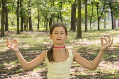 kız mutlu ve yoga parkta, uygulama üzerinde meditasyon yoga çocuk. Sağlıklı yaşam - küçük kız parkta yoga yapıyor. Sağlıklı ve Yoga kavramı.