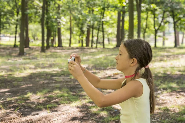 Küçük kız çocuğu 8 yıl Şehir Parkı yeşil çimenlikte oturan kamera bakıyor. Kız 8 yıl doğa fotoğraflarını Park.