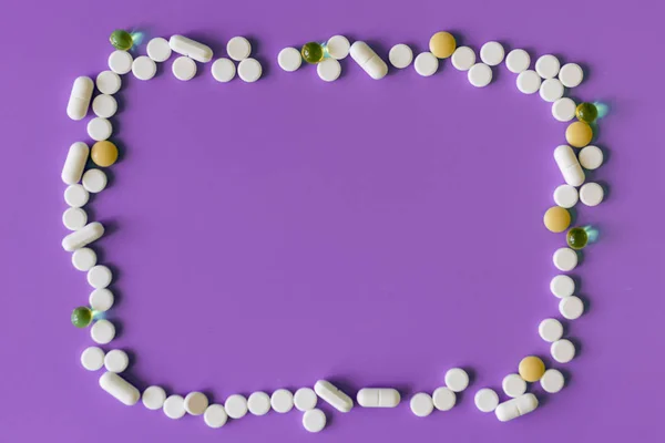 Frame of pills on a purple background. Pills for design. Concept of health, healthy lifestyle. Copy space for advertisement