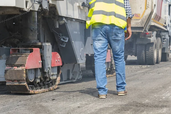 Close view on the workers and the asphalting machines. Machinery for asphalting roads.