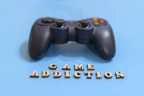 The concept of people\'s game addiction on computer games. dzhostik and the inscription game addiction on a blue background