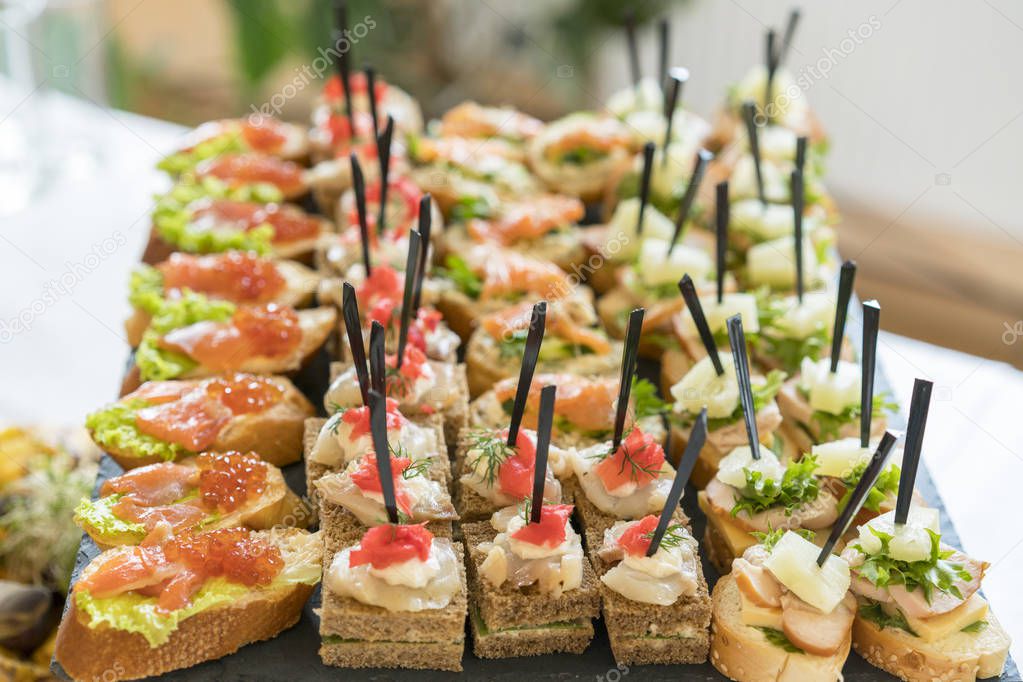 Crostini with different toppings on wooden background. Delicious appetizers. Front view. Gourmet appetizers: caviar, venison, tuna and salmon