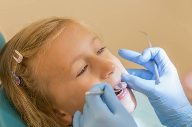 Küçük kız dişçi ofisinde resepsiyonda. sonra diş tedavileri diş hekimi yakın bir sandalyede oturan küçük kız. Dişçi ofisinde küçük kız sitts.