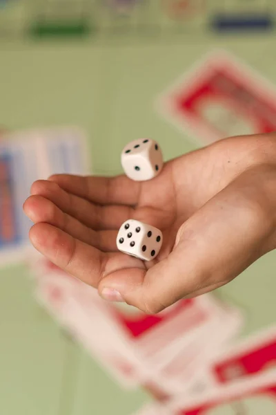 The hand throws game dice on the background of the playing field