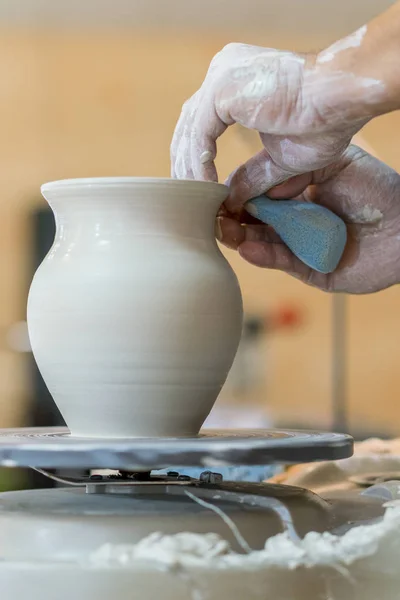 Creating a jar or vase of white clay close-up. Master crock. Man hands making clay jug macro. The sculptor in the workshop makes a jug out of earthenware closeup. vertical photo.