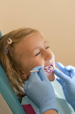 Küçük kız dişçi ofisinde resepsiyonda. sonra diş tedavileri diş hekimi yakın bir sandalyede oturan küçük kız. Küçük kız sitts dişçi ofisinde. dikey fotoğraf.