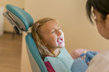 Sarışın kız, diş hekimi. Küçük bir kızın dişleri diş hekimi inceliyor.