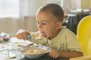 Çocuk 2 yıl püresi yiyor. Çocuk tablo. Çocuğun bağımsızlık kavramı. Yulaf lapası yemek mutlu küçük çocuk. Küçük çocuk masada kahvaltı.