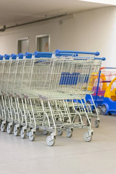 Shopping Trolleys - Supermarket Shopping Theme. Row of shopping carts with blue handles. vertical photo.