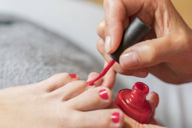 Asıl müşteri çivi ile vernik kapsar. Eldiven umurunda hakkında bir kadının ayak tırnakları eller. Pedikür, manikür güzellik salonu konsept. Kırmızı renkli vernik çivi