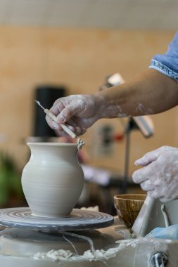 Potter kil Potter's tekerlek üzerinde bir pot kalıpları. Efendinin eller bir potter'ın direksiyonda yaparım. dikey fotoğraf.