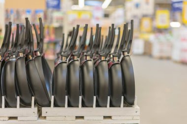 Depodaki bir satır tava yeni asılı. mutfak aletleri. Mağaza raflarında siyah tavalar.