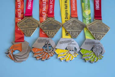 Kiev, Ukraine. September 2 2018 Many different sports medals on a blue background. Medals for half marathon, marathon and other distances. clipart
