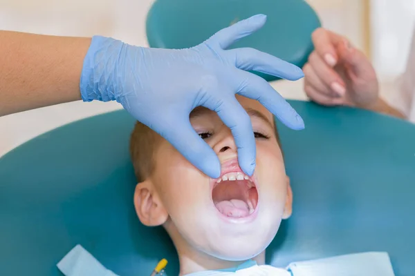 歯科医は 少年の歯を扱っています 子供の歯科 小児歯科 女性口科医は 学齢期の少年の歯を扱っています 口腔の健康と衛生 — ストック写真