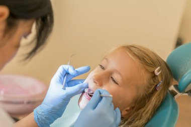 Küçük kız dişçi ofisinde resepsiyonda. sonra diş tedavileri diş hekimi yakın bir sandalyede oturan küçük kız. Diş hekimleri Office küçük kız sitts