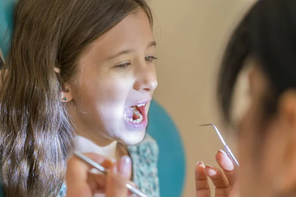 Uma menina na recepção do consultório de dentistas. menina sentada em uma cadeira perto de um dentista após o tratamento dentário. Menina senta-se no consultório de dentistas — Fotografia de Stock