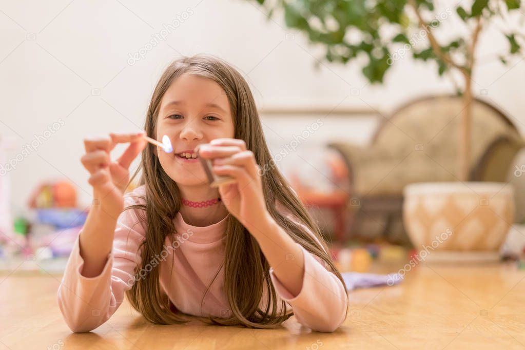 Girl playing with matches. Dangerous situation at home. A small child plays with matches, a fire, a fire flares up, danger, child and matches, lucifer match.