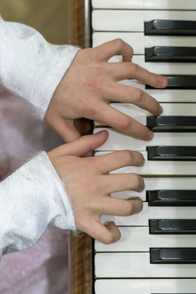 Детские руки на клавишах пианино. вертикальное фото
.