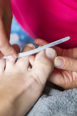 Eldiven umurunda elinde çivi ayak. Pedikür güzellik salonu. Tırnakları ile dosya dosyalama. yakın çekim. verical fotoğraf.