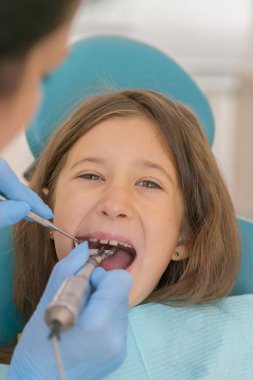 Açık ağız, diş hekimi ile genç çocuğun makro yakın çekim. Diş check-up dişçi ofisinde. Dişçi kız diş diş hekimleri sandalyede incelenmesi. dikey fotoğraf.