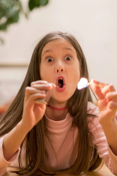 Girl playing with matches. Dangerous situation at home. A small child plays with matches, a fire, a fire flares up, danger, child and matches, lucifer match. vertical photo — Stock Image Girl playing with matches. Dangerous situation at home. A small child plays with matches, a fire, a fire flares up, danger, child and matches, lucifer match. vertical photo Stock Image