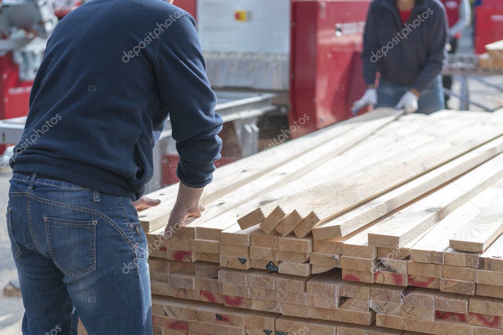 A man works at a sawmill. Man folding boards