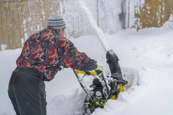 Kar temizleme makinesi ile kaldırımlar kardan bir adam temizler
