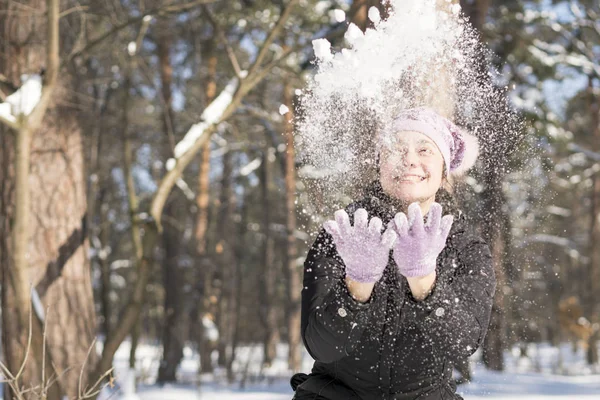 Girl throws snow up. Portrait of the beautiful girl throwing snow in the winter. Happy young woman plays with a snow in sunny winter day.