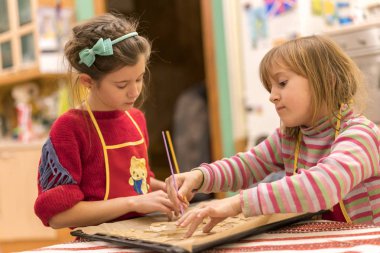 İki kız kardeş 7 ve 5 yıllık aşçı zencefilli bisküvi. Bir mangal hamur yayılır. İki mom'ın yardımcıları.