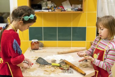 İki kız kardeş 5 ve 7 yıl mutfakta pasta kurabiye yapabilir. İki annenin Yardımcısı
