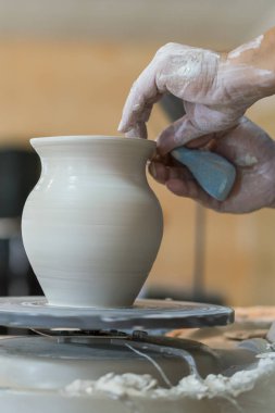 Potter kil Potter's tekerlek üzerinde bir pot kalıpları. Efendinin eller bir potter'ın direksiyonda yaparım. dikey fotoğraf.