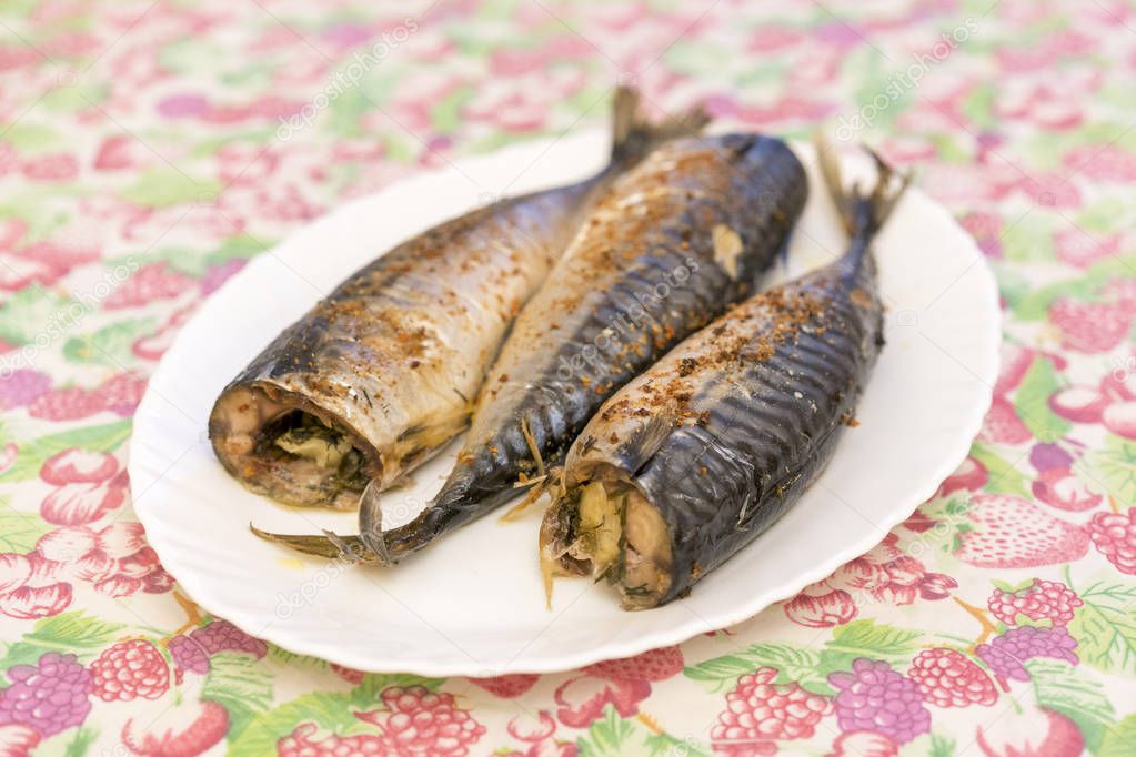 three baked fish on a white plate. Healthy food, seafood. Mackerel.