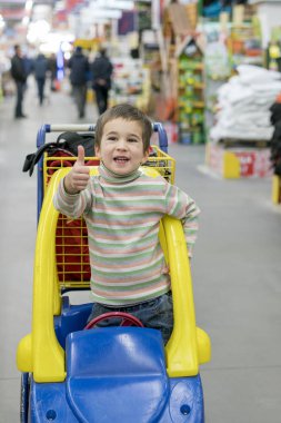 Çocuk 4 yıl Yapı Market Sepetinizde çocuk dışarı doğru eğildi. Çocukların tehlikeli davranış.