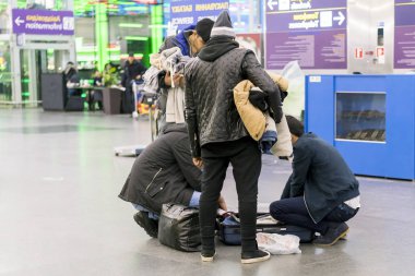 Bir adam havaalanında onu bavul rummages. Bir adam çanta bir şeyler arıyor. Adam havaalanında bir şey kaybetti. insanlar havaalanında bavul içinde bir şey için arıyoruz.