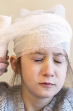 Doktor kızın kafası sargılı.