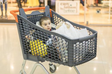 Hangi çocuk oturur ürünleri ile bir arabası. Tam sepeti süpermarket gıda ile. Bir bebek arabasında oturur.